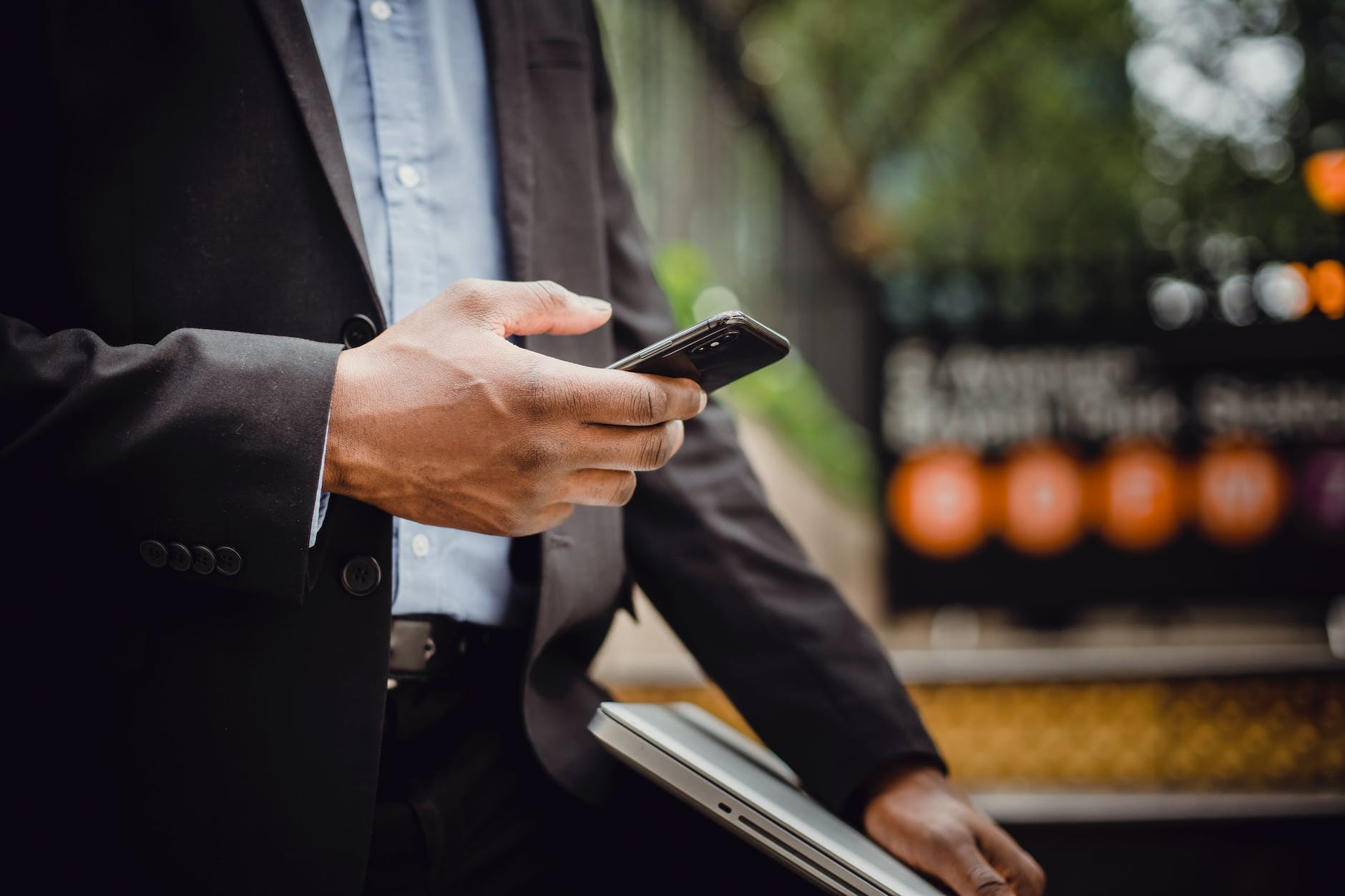 crop black businessman using smartphone on street